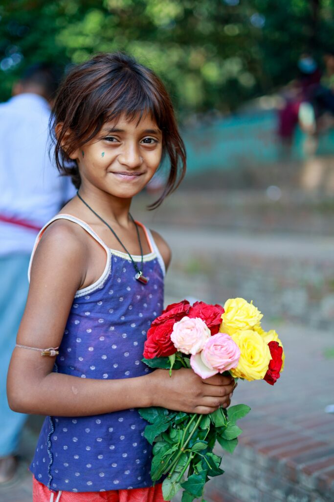 A joyful child holding a colorful bouquet of roses outdoors in Chattogram, Bangladesh.